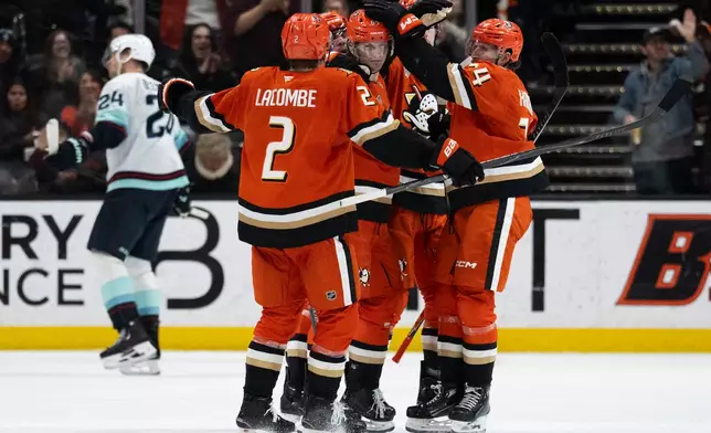 Anaheim Ducks defenseman Jacob Trouba (65) celebrates his goal with defenseman Jackson LaCombe (2) and center Jansen Harkins (24) during the second period of an NHL hockey game against the Seattle Kraken Tuesday, Feb. 3, 2026, in Anaheim, Calif. (AP Photo/Kyusung Gong)