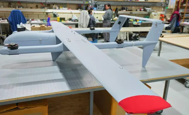 Employees, in the background, work beside an under-construction drone at a manufacturing factory in Limassol, Cyprus, Tuesday, Jan. 27, 2026. (AP Photo/Petros Karadjias)