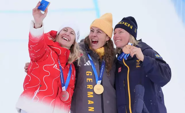 From left, silver medalist Switzerland's Fanny Smith (3), gold medalist Germany's Daniela Maier (1), and bronze medalist Sweden's Sandra Naeslund (2) celebrate after the women's ski cross finals at the 2026 Winter Olympics, in Livigno, Italy, Friday, Feb. 20, 2026. (AP Photo/Rebecca Blackwell)