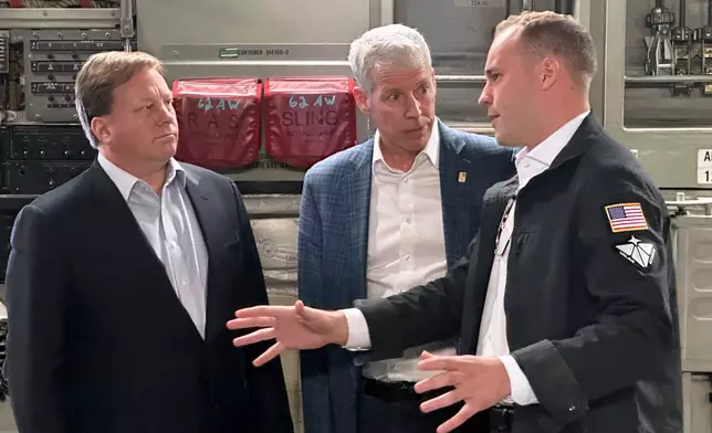 Energy Secretary Chris Wright, center, and Under Secretary of Defense Michael Duffey, left, listen as Isaiah Taylor, CEO of Valar Atomics, discusses a microreactor developed by Valar to generate nuclear power for the military and commercial customers, Sunday, Feb. 15, 2026, in-flight, on board a C-17. (AP Photo/Matthew Daly)