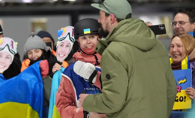 Ukraine's Kateryna Kotsar gets a proposal from Bogdan Fashtryga, front, as she competes in the women's freestyle skiing big air qualifications at the 2026 Winter Olympics, in Livigno, Italy, Saturday, Feb. 14, 2026. (AP Photo/Abbie Parr)