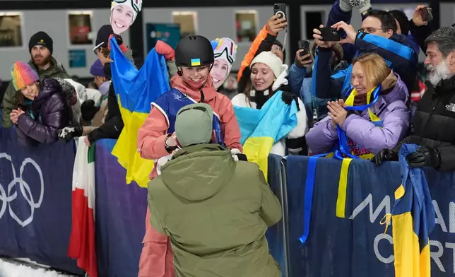Ukraine's Kateryna Kotsar gets a proposal from Bogdan Fashtryga, front, as she competes in the women's freestyle skiing big air qualifications at the 2026 Winter Olympics, in Livigno, Italy, Saturday, Feb. 14, 2026. (AP Photo/Abbie Parr)