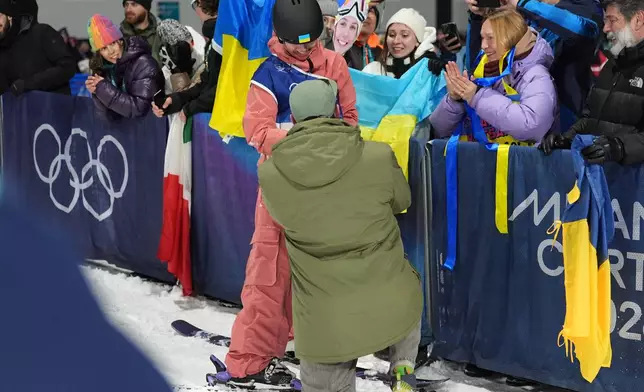 Ukraine's Kateryna Kotsar gets a proposal from Bogdan Fashtryga, front, as she competes in the women's freestyle skiing big air qualifications at the 2026 Winter Olympics, in Livigno, Italy, Saturday, Feb. 14, 2026. (AP Photo/Abbie Parr)