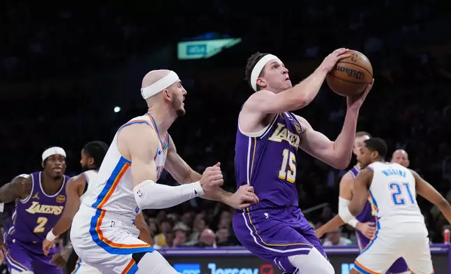 Los Angeles Lakers guard Austin Reaves (15) drives to the basket past Oklahoma City Thunder guard Alex Caruso during the first half of an NBA basketball game Monday, Feb. 9, 2026, in Los Angeles. (AP Photo/Jae C. Hong)