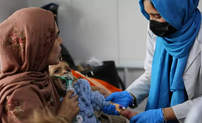 Latifa Bakkar attempts to give oxygen to her severely malnourished 2½-year-old son, Abu Bakar, as a nurse inserts an intravenous cannula into his arm at Indira Gandhi Children's Hospital in Kabul, Afghanistan, Sunday, Feb. 15, 2026. (AP Photo/Siddiqullah Alizai)