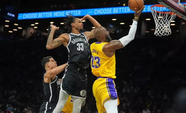 Los Angeles Lakers' LeBron James, right, drives past Brooklyn Nets' Nic Claxton, center, and Michael Porter Jr. during the first half of an NBA basketball game Tuesday, Feb. 3, 2026, in New York. (AP Photo/Frank Franklin II)