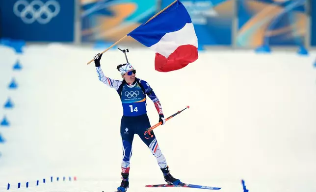 Julia Simon, of France, skis to the finish line with her country's flag for gold in the women's 4x6-kilometer relay biathlon race at the 2026 Winter Olympics in Anterselva, Italy, Wednesday, Feb. 18, 2026. (AP Photo/Andrew Medichini)