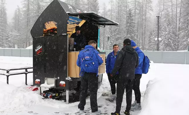 Bobsledders from the United States and Trinidad and Tobago speak at the coffee stand at the Cortina Olympic Village, ahead of the 2026 Winter Olympics, in Cortina d'Ampezzo, Italy, Tuesday, Feb. 3, 2026. (AP Photo/Jennifer McDermott)