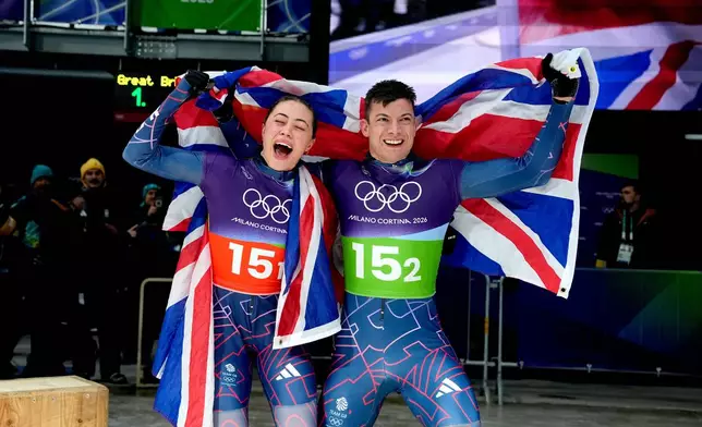 Britain's gold medalists Matt Weston, right, and Britain's Tabitha Stoecker, left, celebrate at the finish during the skeleton mixed team competition at the 2026 Winter Olympics, in Cortina d'Ampezzo, Italy, Sunday, Feb. 15, 2026. (AP Photo/Alessandra Tarantino)