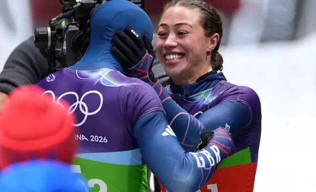 Britain's gold medalists Matt Weston, left, and Britain's Tabitha Stoecker, right, celebrate at the finish during the skeleton mixed team competition at the 2026 Winter Olympics, in Cortina d'Ampezzo, Italy, Sunday, Feb. 15, 2026. (AP Photo/Aijaz Rahi)