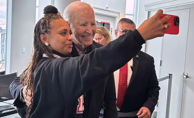 President Joe Biden is greeted by passengers awaiting an outgoing flight and poses for selfies, after his flight arrived, Friday, Feb. 27, 2026 in Columbia, S.C. (AP Photo/Meg Kinnard)