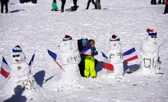Fans take photos with snowmen with the names of France's Eric Perrot, from left, Emilien Jacquelin, Fabien Claude and Quentin Fillon Maillet ahead of the men's 15-kilometer mass start biathlon race at the 2026 Winter Olympics in Anterselva, Italy, Friday, Feb. 20, 2026. (AP Photo/Andrew Medichini)