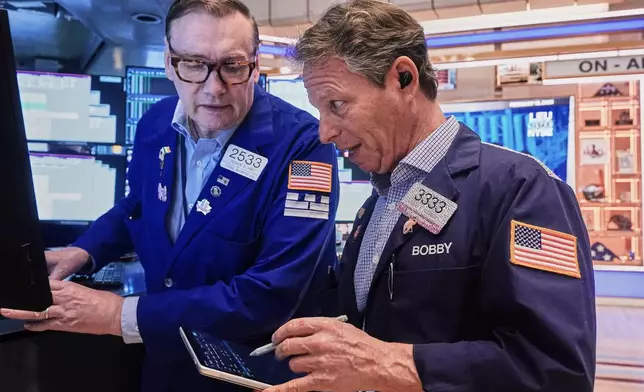 Specialist Patrick King, left, and trader Robert Charmak work on the floor of the New York Stock Exchange, Thursday, Feb. 19, 2026. (AP Photo/Richard Drew)