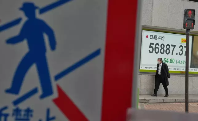 A person walks in front of an electronic stock board showing Japan's Nikkei index at a securities firm Monday, Feb. 16, 2026, in Tokyo. (AP Photo/Eugene Hoshiko)