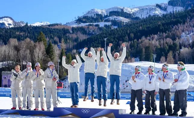 Gold medalists Norway celebrate on the podium flanked by silver medalists France, left, and bronze medalists Italy after the cross country skiing men's 4 x 7.5km relay at the 2026 Winter Olympics, in Tesero, Italy, Sunday, Feb. 15, 2026. (AP Photo/Kirsty Wigglesworth)