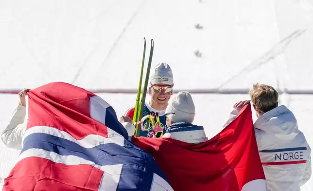 Johannes Hoesflot Klaebo, of Norway, center, joins his teammates Emil Iversen, Martin Loewstroem Nyenget and Einar Hedegart after crossing the finish line to win the gold medal in the cross country skiing men's 4 x 7.5km relay at the 2026 Winter Olympics, in Tesero, Italy, Sunday, Feb. 15, 2026. (AP Photo/Evgeniy Maloletka)