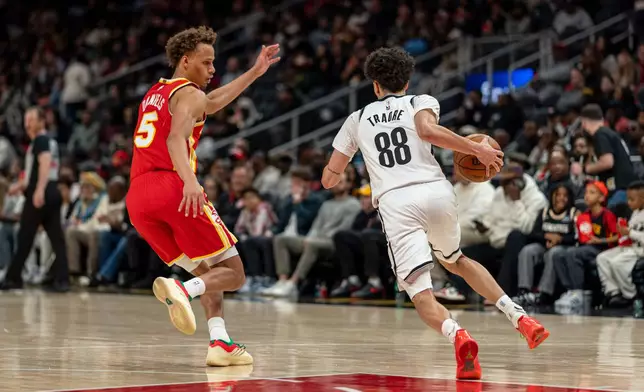 Atlanta Hawks guard Dyson Daniels (5) defends the goal against Brooklyn Nets guard Nolan Traore (88) during the first half of an NBA basketball game, Sunday, Feb. 22, 2026, in Atlanta. (AP Photo/Erik Rank)