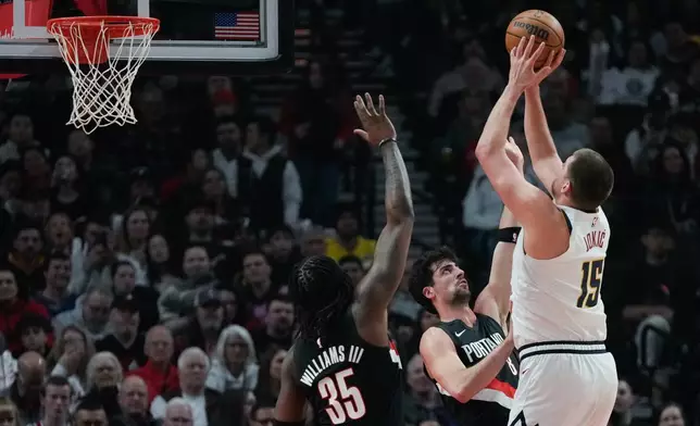 Portland Trail Blazers forward Deni Avdija (8) tries to block a shot by Denver Nuggets center Nikola Jokić (15) during the first half of an NBA basketball game Friday, Feb. 20, 2026, in Portland, Ore. (AP Photo/Jenny Kane)