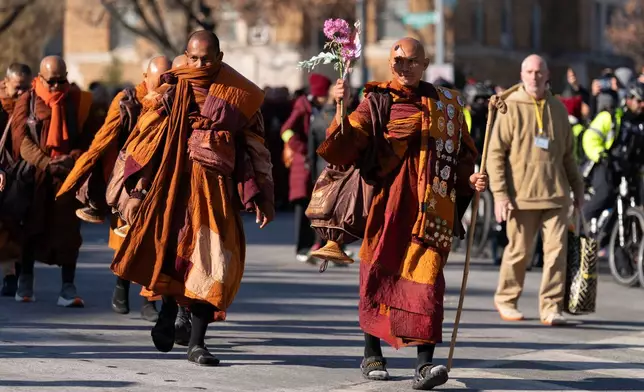 Monk Bhikkhu Pannakara waves as Buddhist monks who are participating in a Walk For Peace walk through a the streets of Washington, Tuesday, Feb. 10, 2026. (AP Photo/Jose Luis Magana)