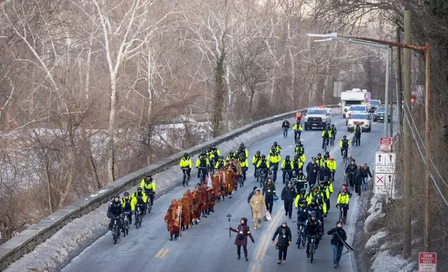 Buddhist monks who are participating in a Walk For Peace are escorted by Metropolitan Police Department officers as they walk along the C&amp;O Canal and Potomac River on Tuesday, Feb. 10, 2026, in Washington. (AP Photo/Mark Schiefelbein)