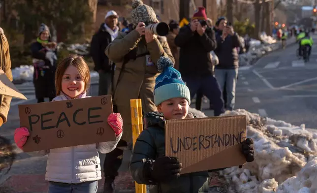 Spectators watch as Buddhist monks who are participating in a Walk For Peace walk through a neighborhood on Tuesday, Feb. 10, 2026, in Washington. (AP Photo/Mark Schiefelbein)