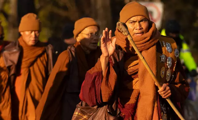 Monk Bhikkhu Pannakara waves as Buddhist monks who are participating in a Walk For Peace walk through a neighborhood on Tuesday, Feb. 10, 2026, in Washington. (AP Photo/Mark Schiefelbein)