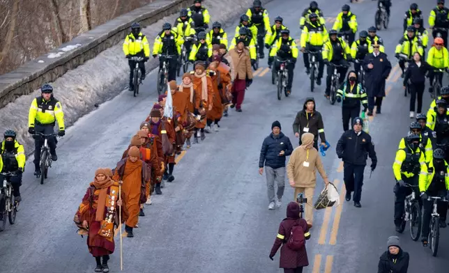 Buddhist monks who are participating in a Walk For Peace are escorted by Metropolitan Police officers as they walk along the C&amp;O Canal and Potomac River on Tuesday, Feb. 10, 2026, in Washington. (AP Photo/Mark Schiefelbein)