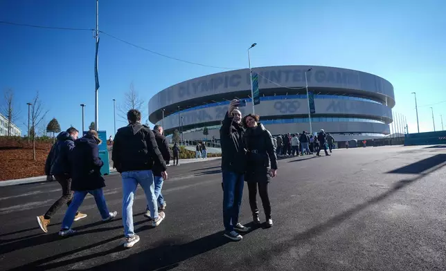 Spectators pose for a selfie outside Milano Santagiulia ice hockey arena before Italy and France play a women's hockey game at the Milan Cortina Winter Olympics, in Milan, on Thursday, Feb. 5, 2026. (Darryl Dyck /The Canadian Press via AP)