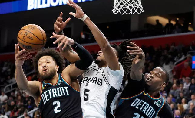 Detroit Pistons guard Cade Cunningham (2) battles San Antonio Spurs guard Stephon Castle (5) for a rebound with Pistons guard Javonte Green (31) helping on the play during the first half of an NBA basketball game Monday, Feb. 23, 2026, in Detroit. (AP Photo/Duane Burleson)