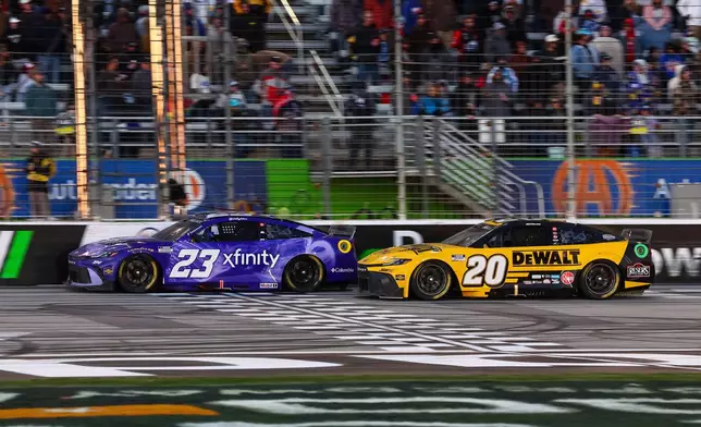 Bubba Wallace (23) and Christopher Bell (20) move on the track during a NASCAR Cup Series auto race, Sunday, Feb. 22, 2026, in Hampton, Ga. (AP Photo/Colin Hubbard)