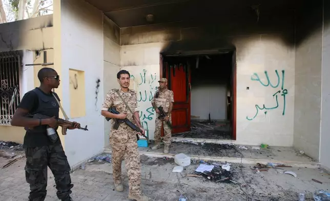 FILE - Libyan military guards check one of the U.S. Consulate's burnt-out buildings, Sept. 14, 2012, during a visit by Libyan President Mohammed el-Megarif, not pictured, to the U.S. Consulate to express sympathy for the death of American ambassador Chris Stevens and his colleagues after the deadly attack on the Consulate on Sept. 11, in Benghazi, Libya. (AP Photo/Mohammad Hannon, File)