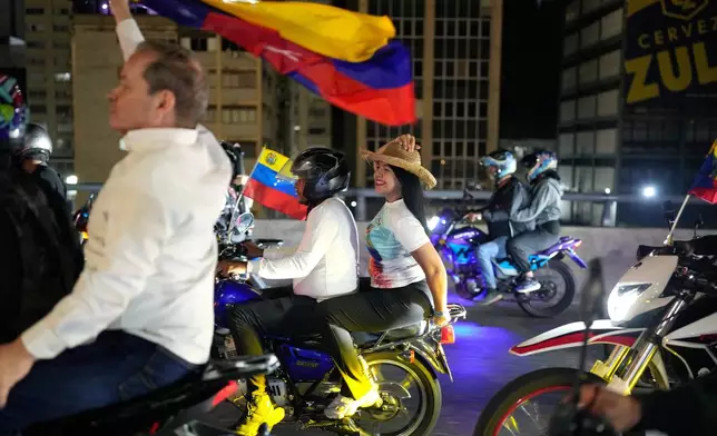 Opposition leaders María Oropeza and Juan Pablo Guanipa, left, ride motorbikes through Caracas, Venezuela, after their release from custody, Sunday, Feb. 8, 2026. (AP Photo/Ariana Cubillos)