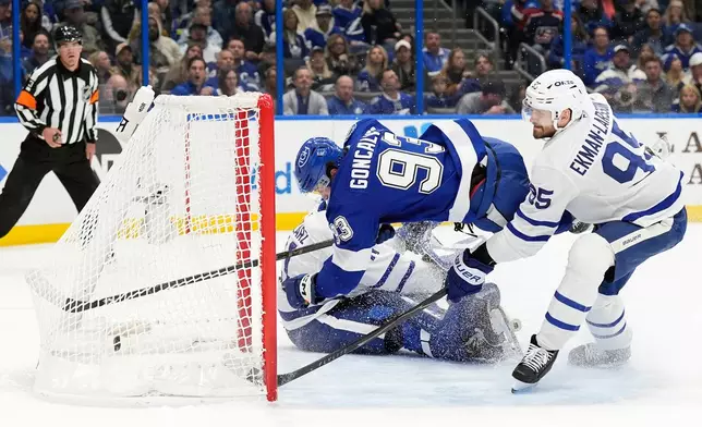 Tampa Bay Lightning center Gage Goncalves (93) gets tripped up by Toronto Maple Leafs defenseman Oliver Ekman-Larsson (95) after scoring past goaltender Anthony Stolarz (41) during the second period of an NHL hockey game Wednesday, Feb. 25, 2026, in Tampa, Fla. (AP Photo/Chris O'Meara)