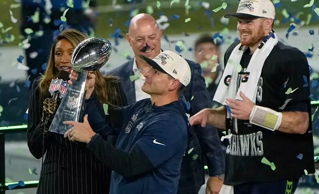 Seattle Seahawks head coach Mike Macdonald holds the trophy as quarterback Sam Darnold, right, and others look on after the team's win in the NFL Super Bowl 60 football game against the New England Patriots, Sunday, Feb. 8, 2026, in Santa Clara, Calif. (AP Photo/Charlie Riedel)