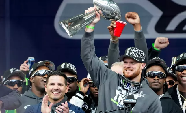 Seattle Seahawks quarterback Sam Darnold holds the Lombardi Trophy as head coach Mike MacDonald celebrates at left during the team's NFL football Super Bowl 60 celebration at Lumen Field, Wednesday, Feb. 11, 2026, in Seattle. (AP Photo/Stephen Brashear)