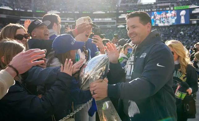 Seattle Seahawks head coach Mike MacDonald holds the Lombardi Trophy and greets fans as he arrives for the team's NFL football Super Bowl 60 celebration at Lumen Field, Wednesday, Feb. 11, 2026, in Seattle. (AP Photo/Stephen Brashear)