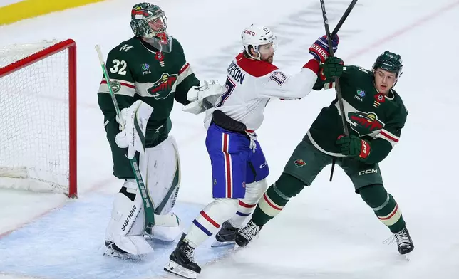 Minnesota Wild defenseman Brock Faber, right, and Montréal Canadiens right wing Josh Anderson, center, compete for position as Wild goaltender Filip Gustavsson defends his net during the second period of an NHL hockey game Monday, Feb. 2, 2026, in St. Paul, Minn. (AP Photo/Matt Krohn)