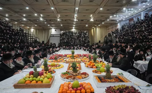 Ultra-Orthodox Jews from the Sanz Hasidic dynasty gather around long table with fruit to celebrate the Jewish holiday of Tu Bishvat, the "New Year of the Trees," in Netanya, Israel, Monday, Feb. 2, 2026. (AP Photo/Ariel Schalit)