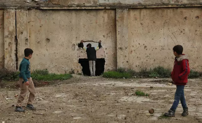 Youths play near a damaged school in the Kurdish-majority neighborhood of Sheikh Maqsoud, in Aleppo, Syria, Saturday, Feb. 14, 2026. (AP Photo/Ghaith Alsayed)