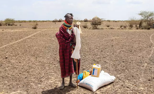 A woman stands beside her food ration after distribution of aid, in Nalemkais Village, Turkana County, Kenya, Sunday, Feb. 8, 2026. (AP Photo/Patrick Ngugi)