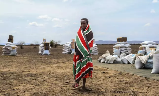 A child stands in front of food aid supplied by the World Food Programme (WFP) ahead of distribution in Nalemkais Village, Turkana County, Kenya, Sunday, Feb. 8, 2026. (AP Photo/Patrick Ngugi)