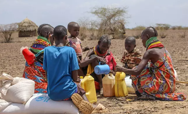 Locals share food rations distributed by World Vision Kenya as severe drought continues, in Nalemkais Village, Turkana County, Kenya, Sunday, Feb. 8, 2026. (AP Photo/Patrick Ngugi)