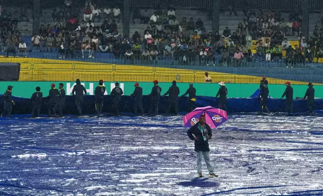 The pitch curator inspects and groundsmen cover the field as it begins to rain before the start of the T20 World Cup cricket match between New Zealand and Pakistan in Colombo, Sri Lanka, Saturday, Feb. 21, 2026. (AP Photo/Eranga Jayawardena)
