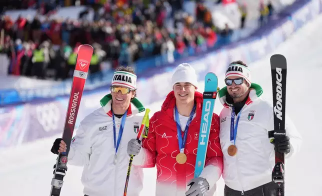 Switzerland's Franjo von Allmen, gold medal in an alpine ski men's downhill race, center, celebrates with silver medalist Italy's Giovanni Franzoni, left, and bronze medalist Italy's Dominik Paris at the 2026 Winter Olympics, in Bormio, Italy, Saturday, Feb. 7, 2026. (AP Photo/Rebecca Blackwell)