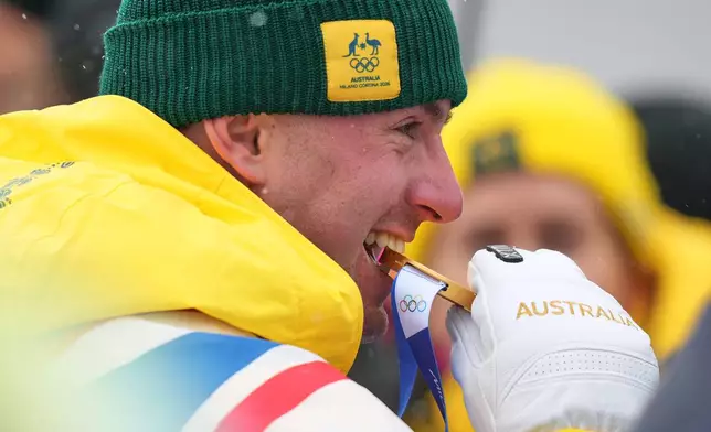 Australia's Cooper Woods bites his gold medal after the men's freestyle skiing moguls finals at the 2026 Winter Olympics, in Livigno, Italy, Thursday, Feb. 12, 2026. (AP Photo/Abbie Parr)