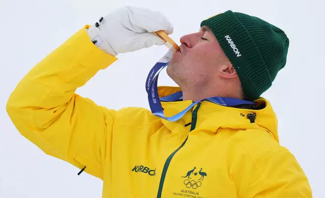 Australia's Cooper Woods kisses his gold medal after the men's freestyle skiing moguls finals at the 2026 Winter Olympics, in Livigno, Italy, Thursday, Feb. 12, 2026. (AP Photo/Abbie Parr)