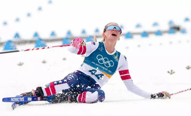 Jessie Diggins, of the United States, falls to the ground after crossing the finish line in the cross country skiing women's 10km interval start free at the 2026 Winter Olympics, in Tesero, Italy, Thursday, Feb. 12, 2026. (AP Photo/Kirsty Wigglesworth)