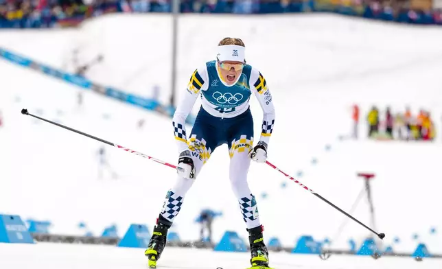 Frida Karlsson, of Sweden, crosses the finish line in the cross country skiing women's 10km interval start free at the 2026 Winter Olympics, in Tesero, Italy, Thursday, Feb. 12, 2026. (AP Photo/Kirsty Wigglesworth)