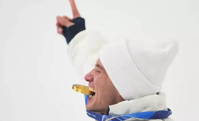 Gold medalist United States' Alex Ferreira bites his medal as he celebrates his win after the men's freestyle skiing halfpipe finals at the 2026 Winter Olympics, in Livigno, Italy, Friday, Feb. 20, 2026. (AP Photo/Lindsey Wasson)