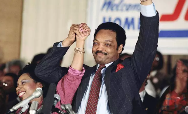 FILE - Democratic presidential hopeful Jesse Jackson with his wife, Jacqueline, salutes the cheering crowd at Operation Push in Chicago, March 10, 1988. (AP Photo/Fred Jewell, File)